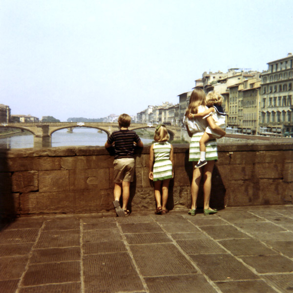 A woman and three children standing on a bridge